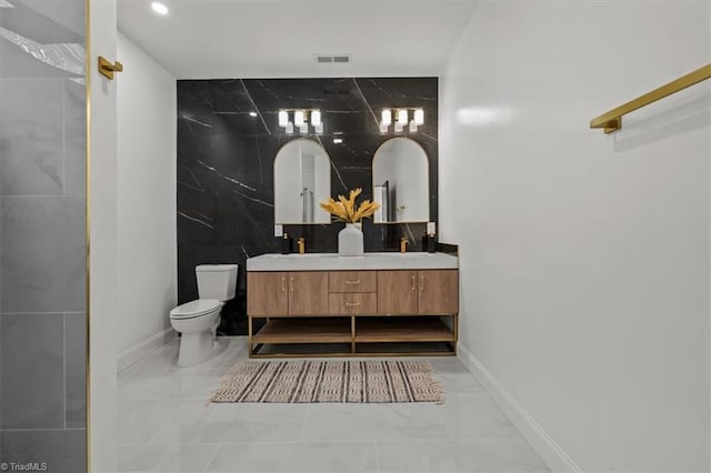 7126 Whitetail Dr, Julian, NC 27283 - bathroom featuring visible vents, double vanity, marble finish floor, toilet, and tile walls