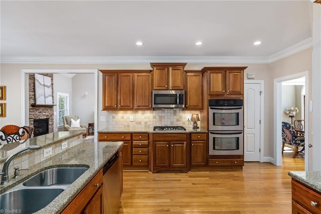 kitchen featuring brown cabinets, appliances with stainless steel finishes, a sink, and light wood-style floors