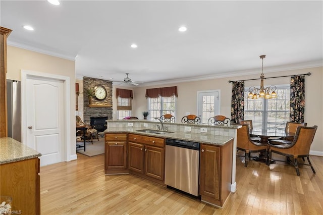 kitchen with brown cabinetry, light wood-style flooring, ornamental molding, stainless steel appliances, and a sink