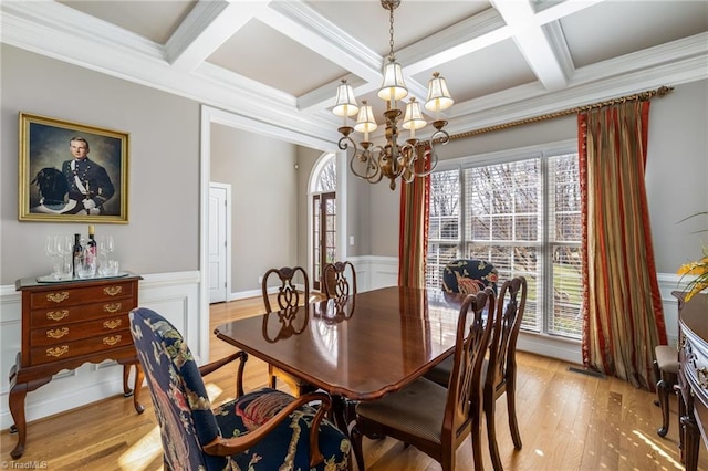 dining area with light wood-style floors, a chandelier, coffered ceiling, and beam ceiling