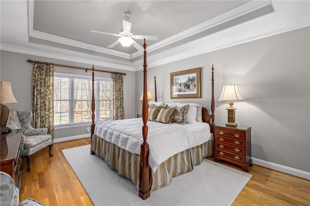 bedroom featuring light wood-type flooring, baseboards, and a tray ceiling