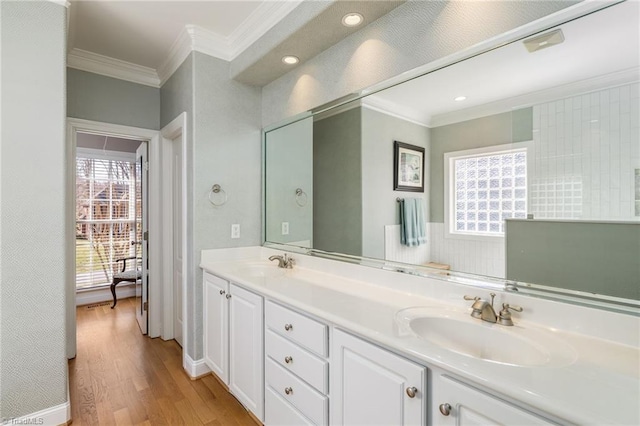 bathroom with double vanity, crown molding, a sink, and wood finished floors