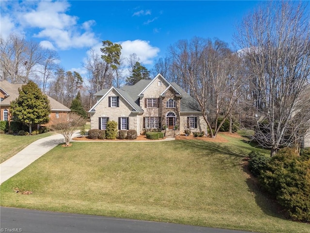 view of front of property featuring a front yard, stone siding, and concrete driveway