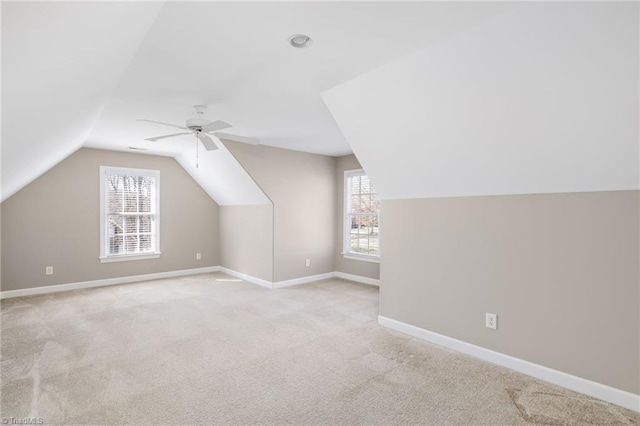 additional living space featuring baseboards, vaulted ceiling, a ceiling fan, and light colored carpet