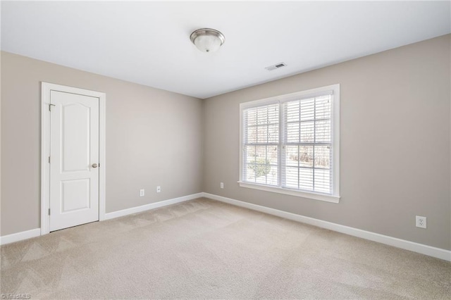 spare room with light carpet, baseboards, and visible vents