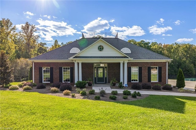 view of front of house with a shingled roof, brick siding, and a front lawn