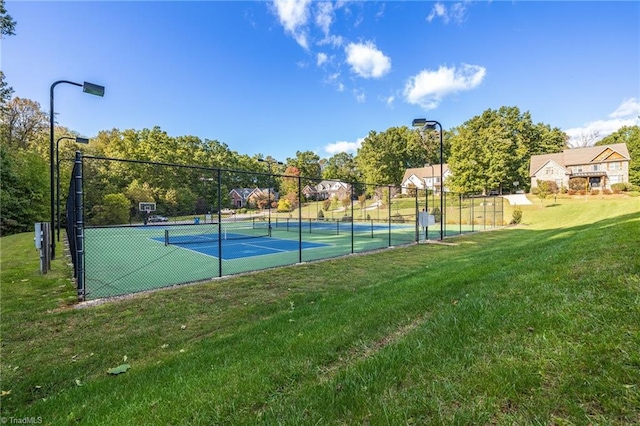 view of sport court with a lawn and fence