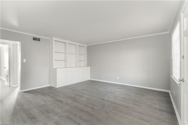 unfurnished room with built in shelves, hardwood / wood-style flooring, and ornamental molding