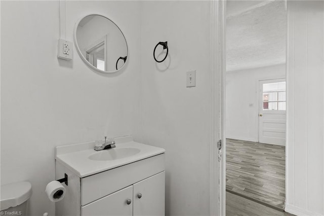 bathroom featuring wood-type flooring, vanity, toilet, and a textured ceiling