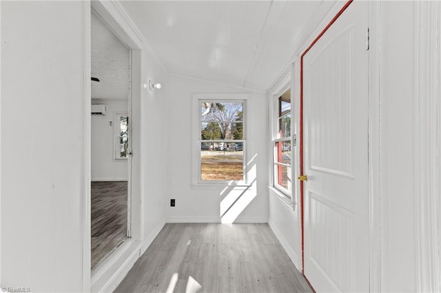 entryway featuring light wood-type flooring, vaulted ceiling, and a wall unit AC