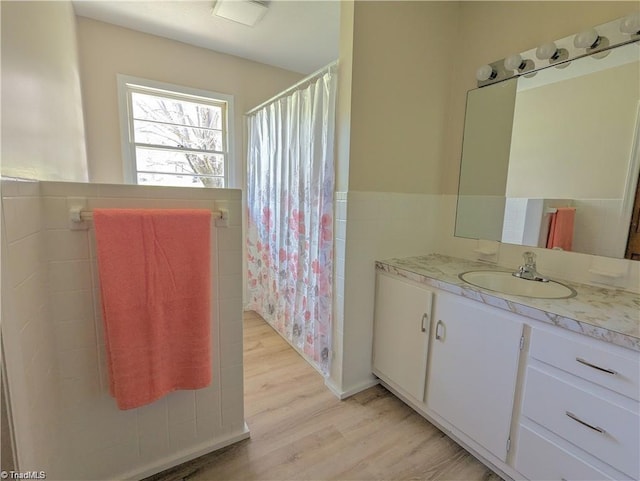 bathroom with vanity, curtained shower, wood finished floors, and tile walls