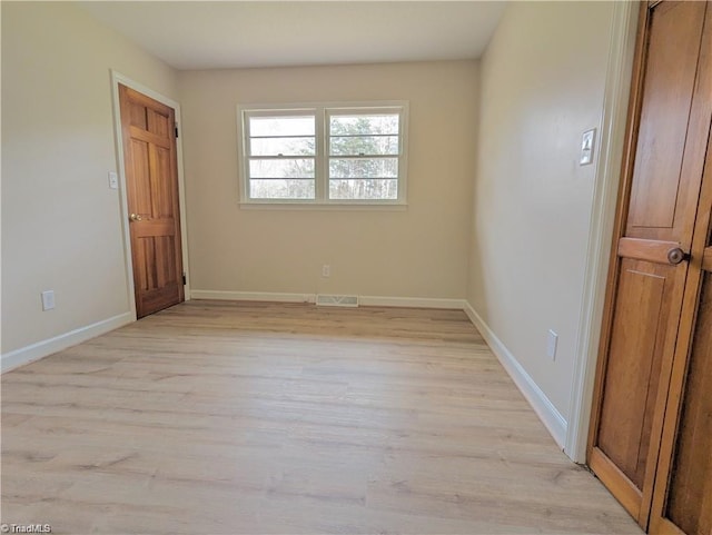 empty room with baseboards, light wood finished floors, and visible vents