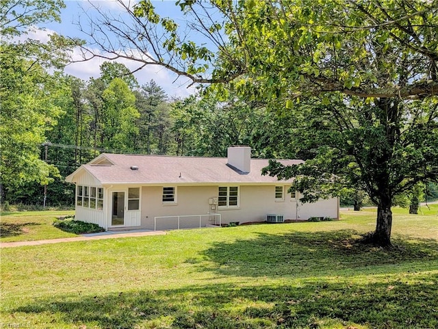 back of property with a lawn, central AC unit, and a chimney