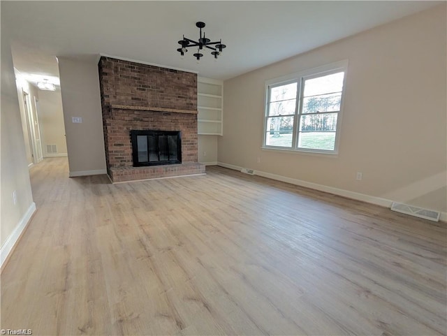 unfurnished living room featuring baseboards, a chandelier, visible vents, and light wood-style floors