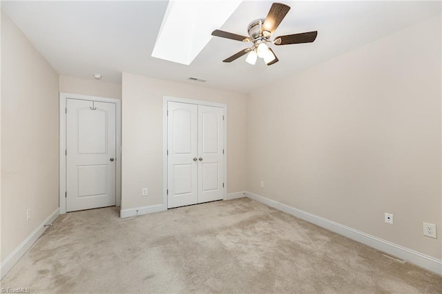 unfurnished bedroom with light colored carpet, ceiling fan, and a skylight