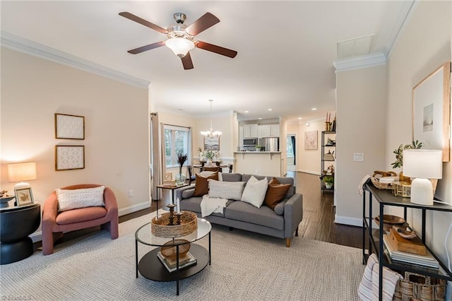 living room with ceiling fan with notable chandelier, wood-type flooring, and ornamental molding