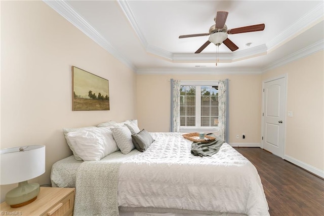 bedroom with dark wood-type flooring, ceiling fan, a tray ceiling, and crown molding