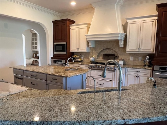 6792 Meadow View Dr, Summerfield, NC 27358 - kitchen featuring appliances with stainless steel finishes, custom range hood, light stone countertops, crown molding, and an island with sink