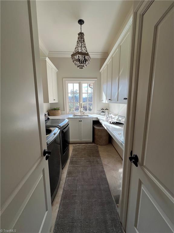 6792 Meadow View Dr, Summerfield, NC 27358 - laundry area featuring cabinet space, washing machine and dryer, a chandelier, ornamental molding, and light tile patterned floors