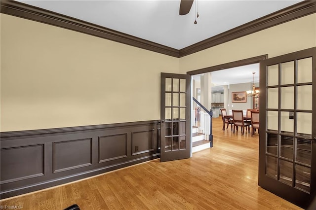 6122 Olde Fields Way, Pfafftown, NC 27040 - unfurnished room featuring ornamental molding, a chandelier, light wood-style floors, a ceiling fan, and a wainscoted wall