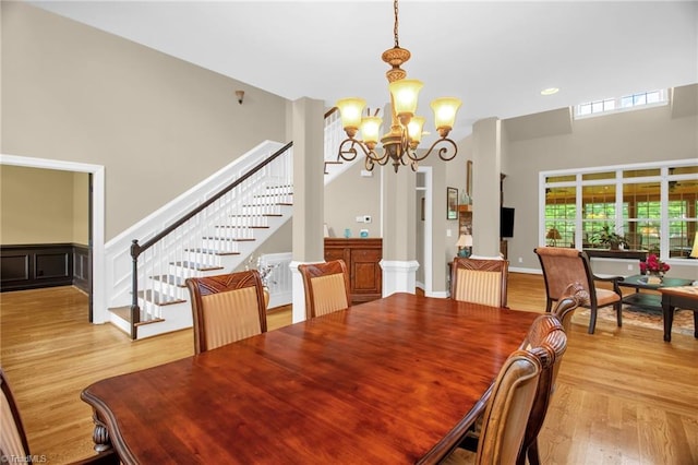 6122 Olde Fields Way, Pfafftown, NC 27040 - dining room featuring stairway, a chandelier, light wood-style flooring, and a towering ceiling