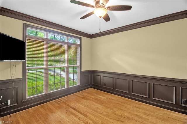 6122 Olde Fields Way, Pfafftown, NC 27040 - spare room featuring crown molding, a wainscoted wall, a ceiling fan, light wood-type flooring, and a decorative wall