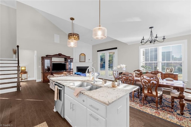 kitchen with pendant lighting, light stone counters, white cabinets, a center island with sink, and stainless steel dishwasher