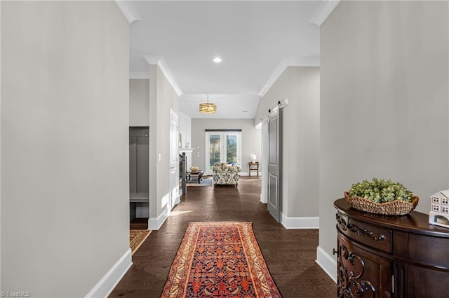 hall featuring ornamental molding, a barn door, and dark hardwood / wood-style floors