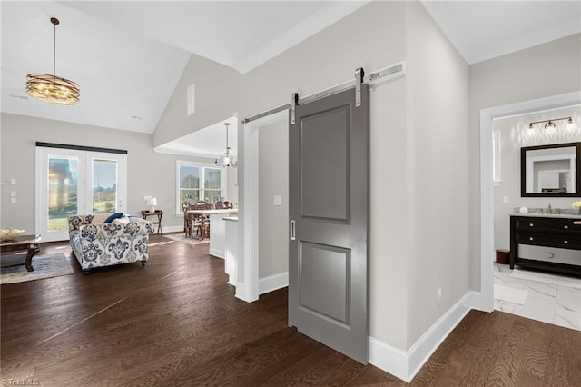 hallway featuring lofted ceiling, a barn door, dark hardwood / wood-style flooring, and sink