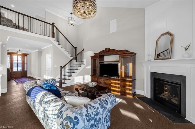 living room with dark hardwood / wood-style flooring, crown molding, and a towering ceiling