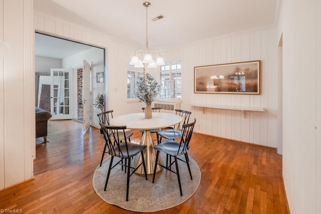 dining area featuring an inviting chandelier, crown molding, and hardwood / wood-style floors