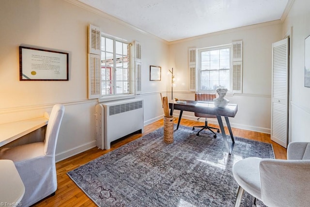 home office with ornamental molding, a healthy amount of sunlight, radiator, and wood-type flooring