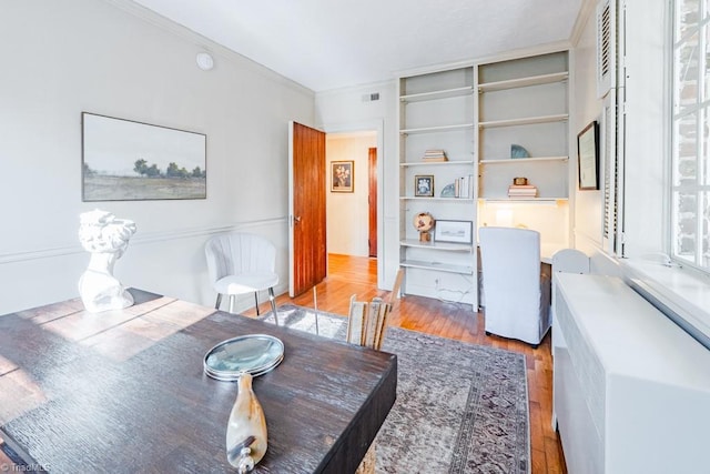 dining room with ornamental molding and light hardwood / wood-style flooring