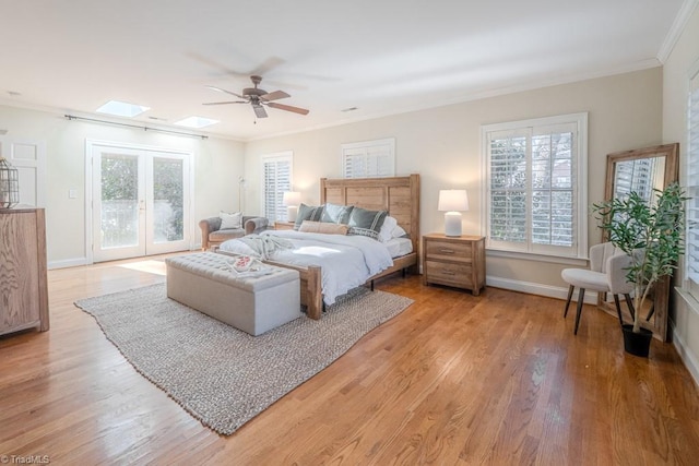 bedroom featuring a skylight, ornamental molding, access to outside, ceiling fan, and light hardwood / wood-style floors