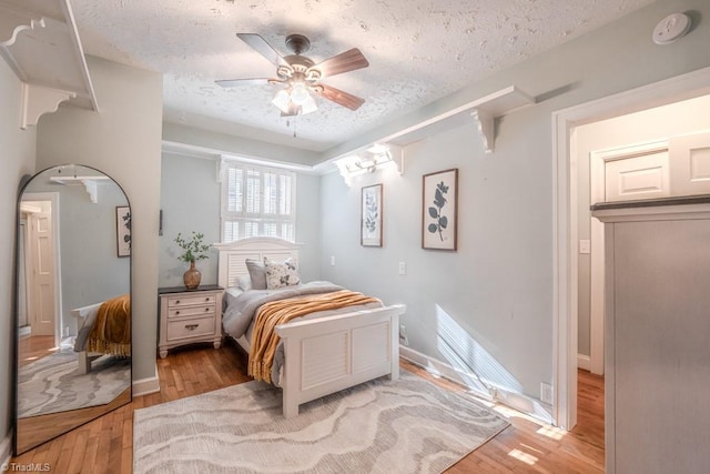 bedroom featuring ceiling fan, a textured ceiling, and light wood-type flooring