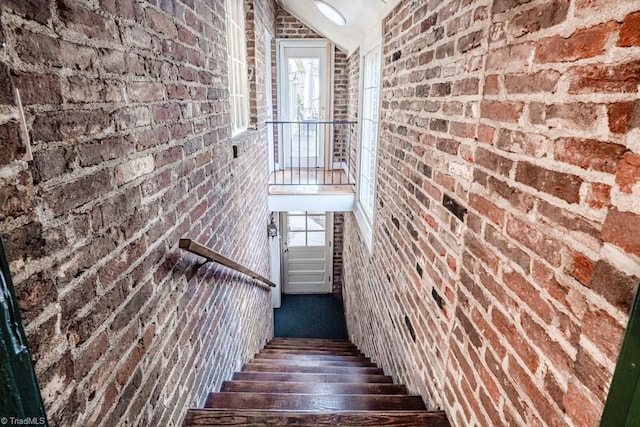 stairway featuring hardwood / wood-style flooring and brick wall