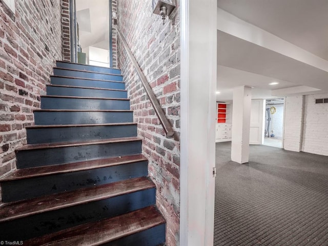 stairs with carpet and brick wall