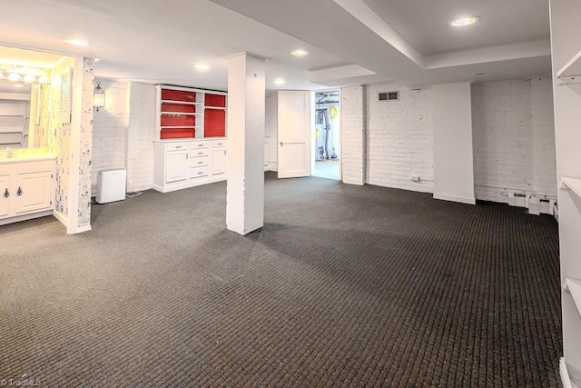 basement with brick wall and dark colored carpet