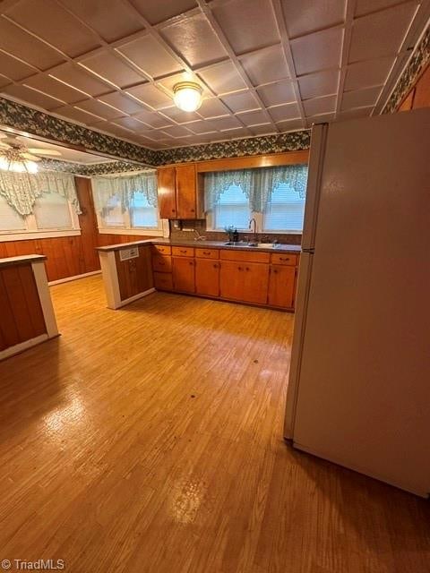 kitchen featuring white refrigerator, sink, light hardwood / wood-style floors, and kitchen peninsula