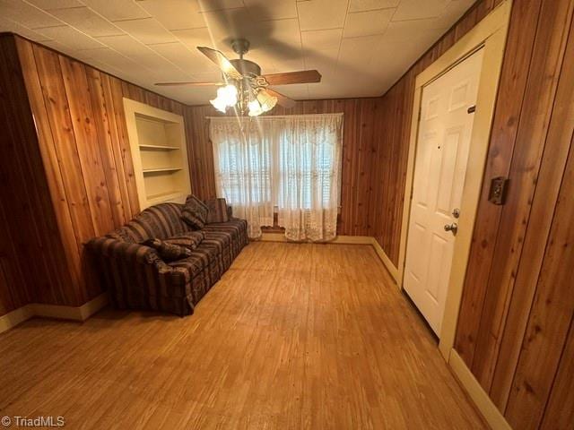 sitting room with hardwood / wood-style flooring, built in features, and wooden walls