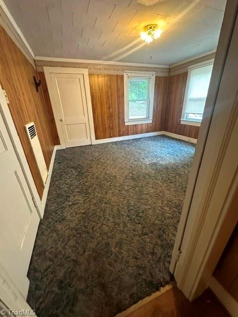 unfurnished bedroom featuring wooden walls, carpet floors, and crown molding