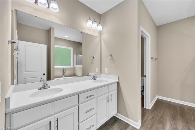 full bath with wood finished floors, double vanity, and baseboards