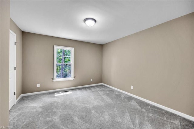 carpeted spare room featuring baseboards
