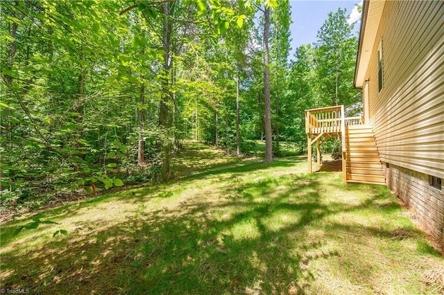 view of grassy yard featuring stairs and a wooden deck