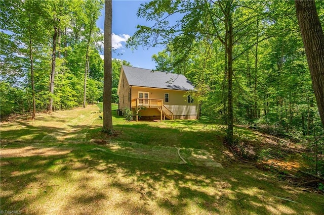 rear view of property with stairway, a wooden deck, and a lawn