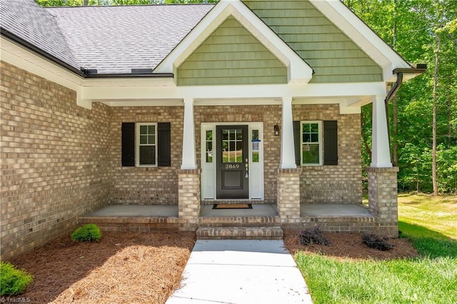 entrance to property with covered porch and brick siding