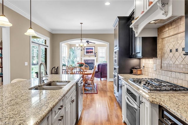 kitchen with white cabinetry, stainless steel appliances, decorative light fixtures, and sink