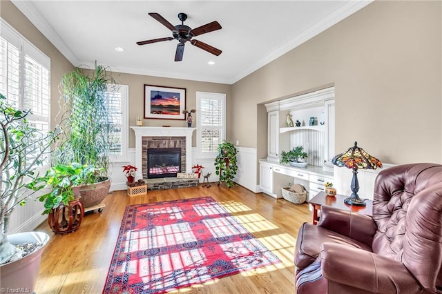 living room featuring a stone fireplace, ornamental molding, and a healthy amount of sunlight