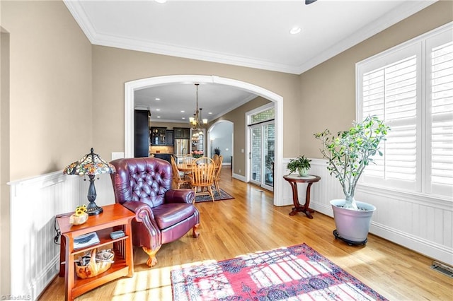 sitting room with an inviting chandelier, hardwood / wood-style floors, and crown molding