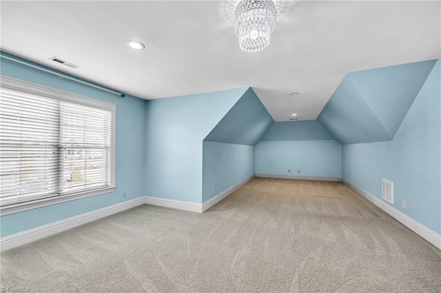 additional living space with a chandelier, vaulted ceiling, and light carpet